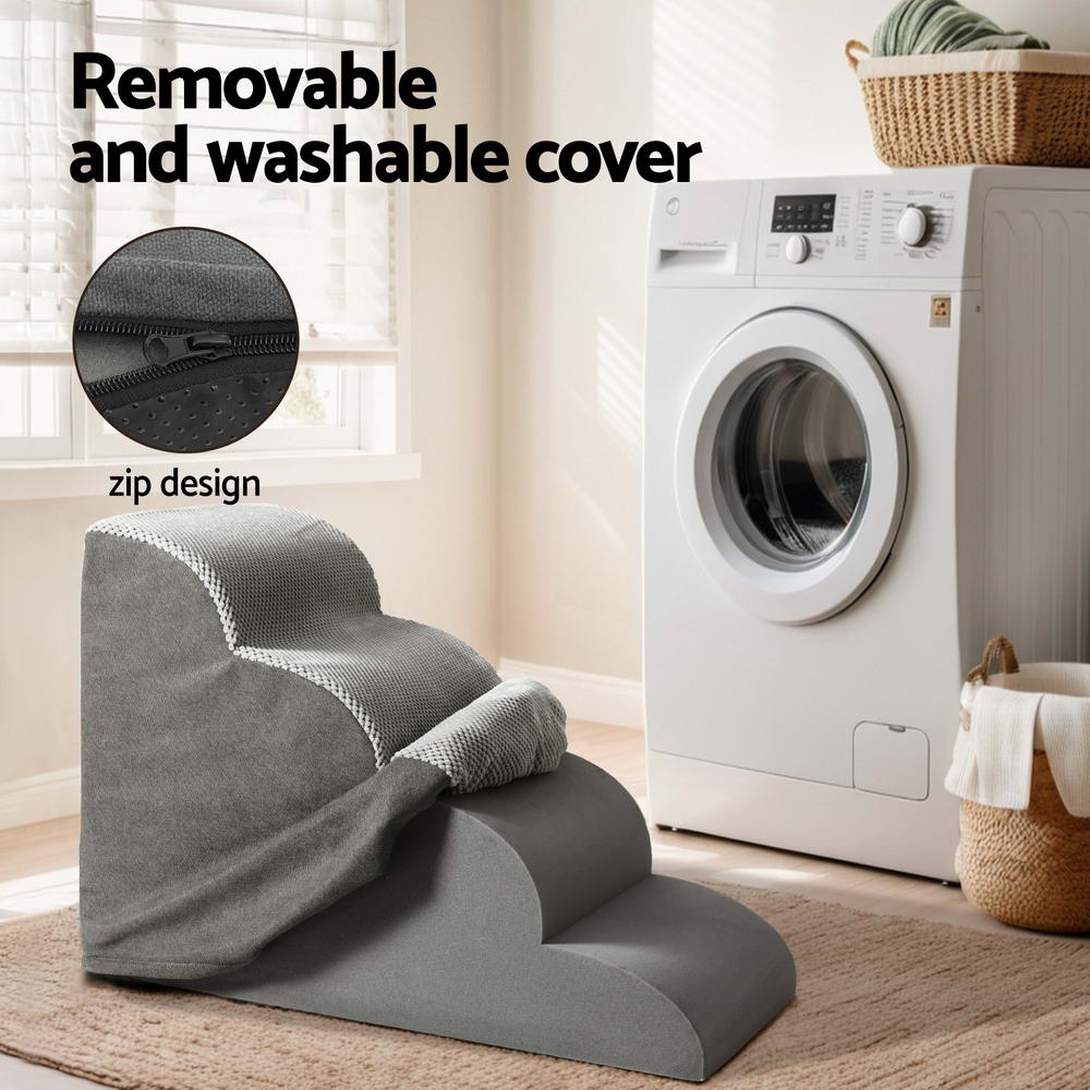 Gray pet step with removable cover next to a washing machine in a laundry room.